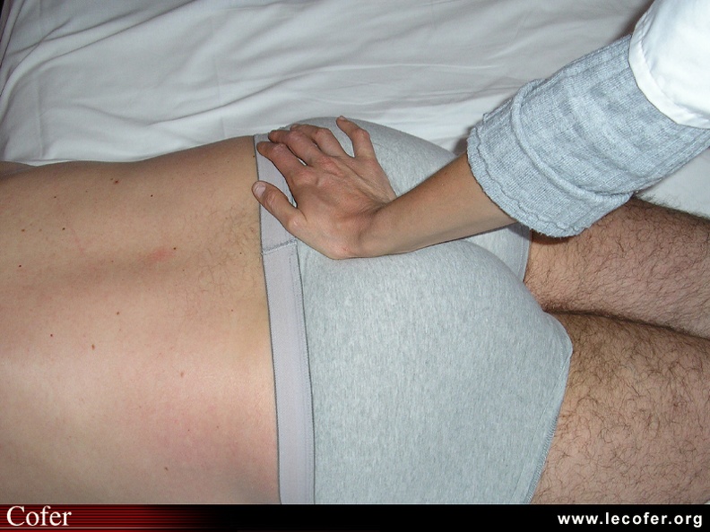 Examen clinique de la sacro-iliaque : manœuvre du trépied : appui du talon de la main sur le sacrum, patient en décubitus ventral. 020201039.jpg
